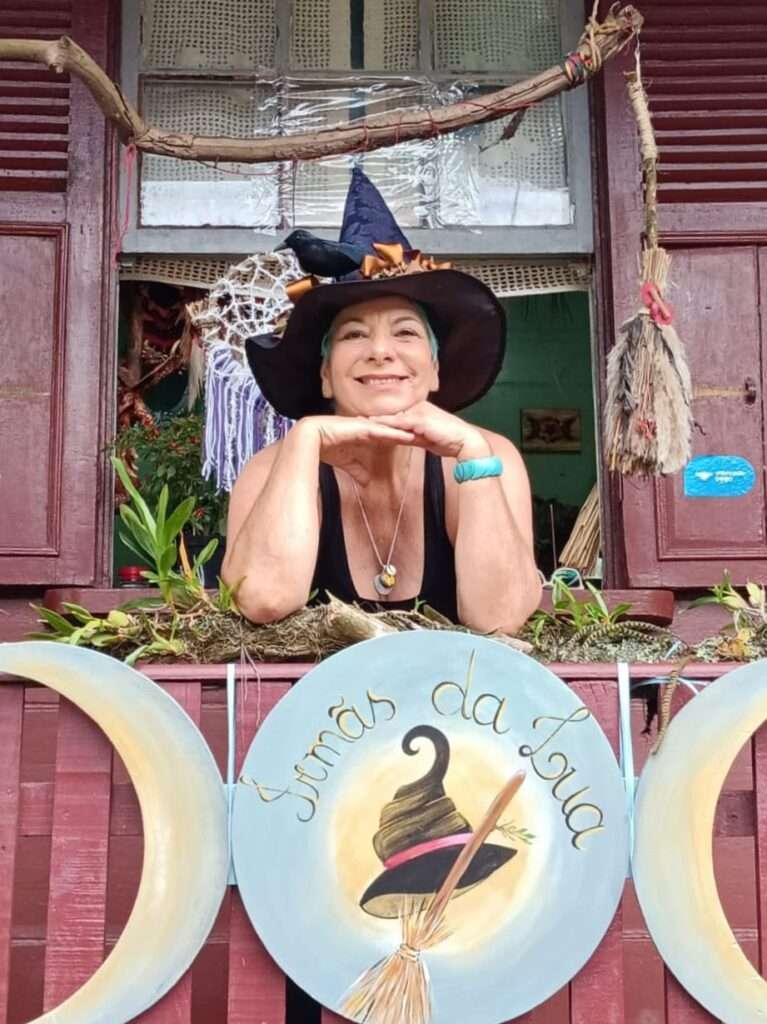mulher com chapéu de bruxa posa em uma janela