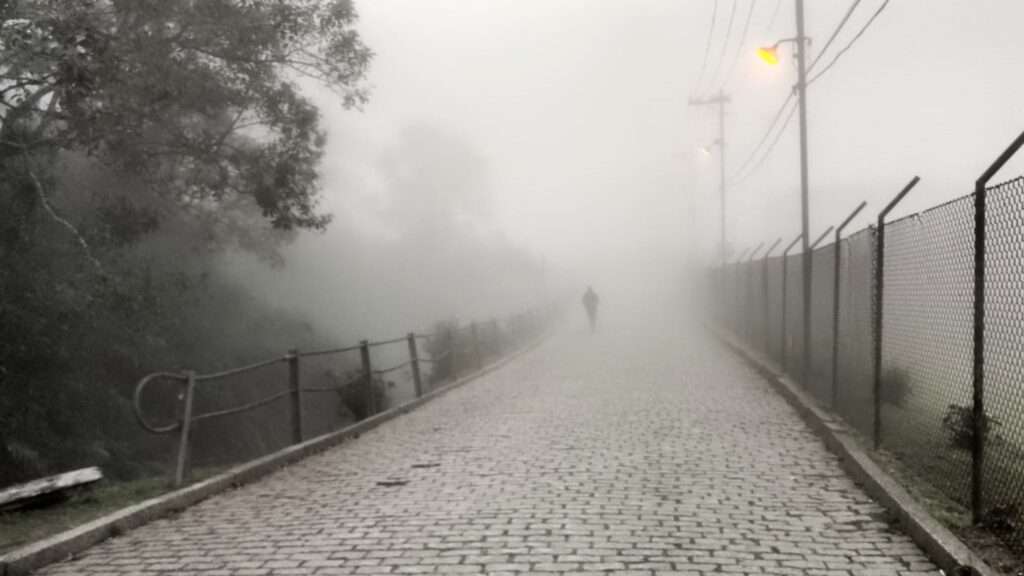 Humano atravessa uma ponte com muita neblina