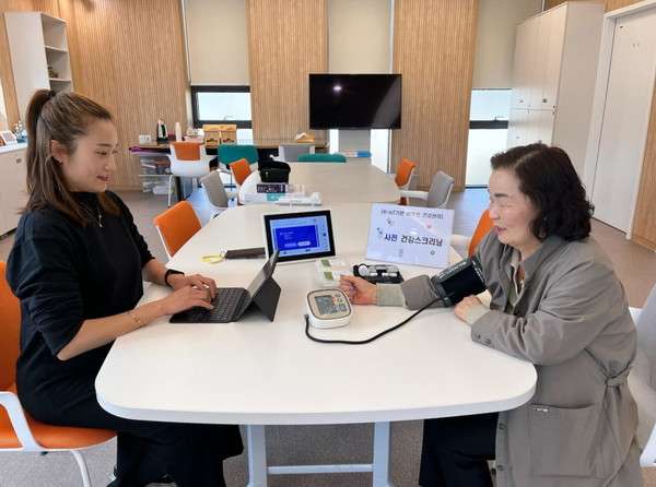 Jovem e idosa sentadas na mesa mediadas por tecnologia