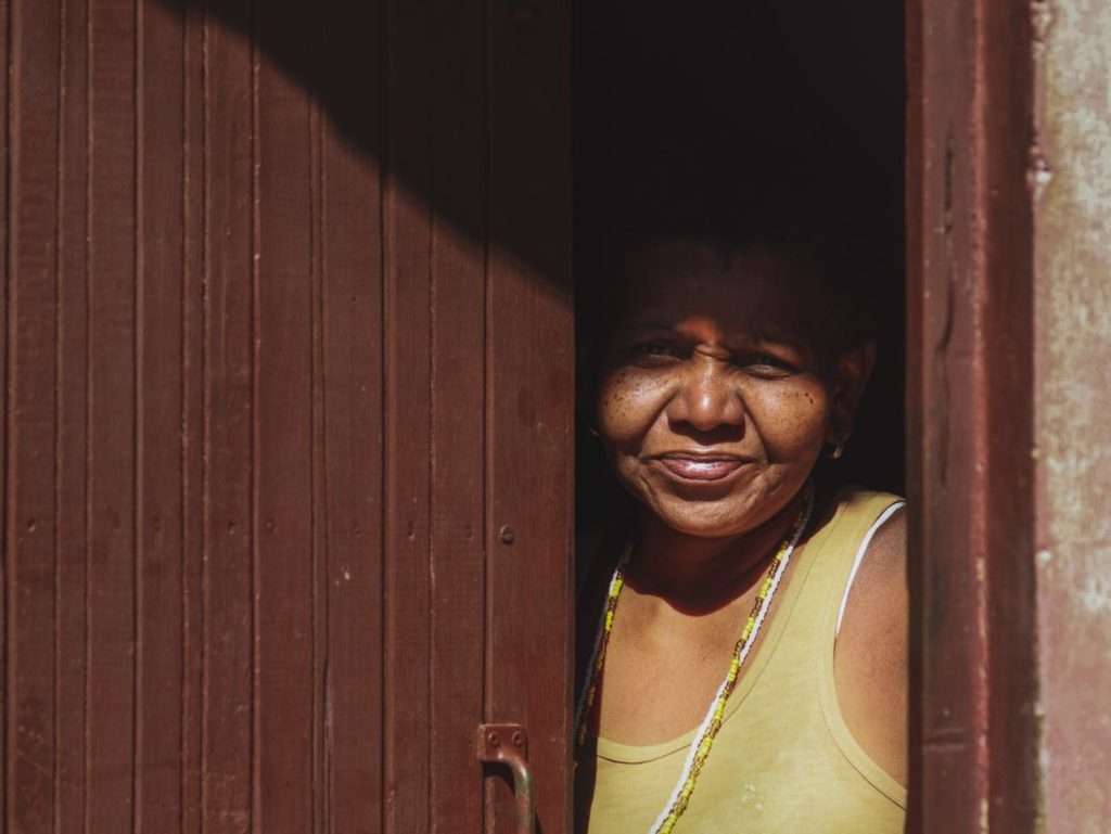 Mulher de regata amarela olha pela porta