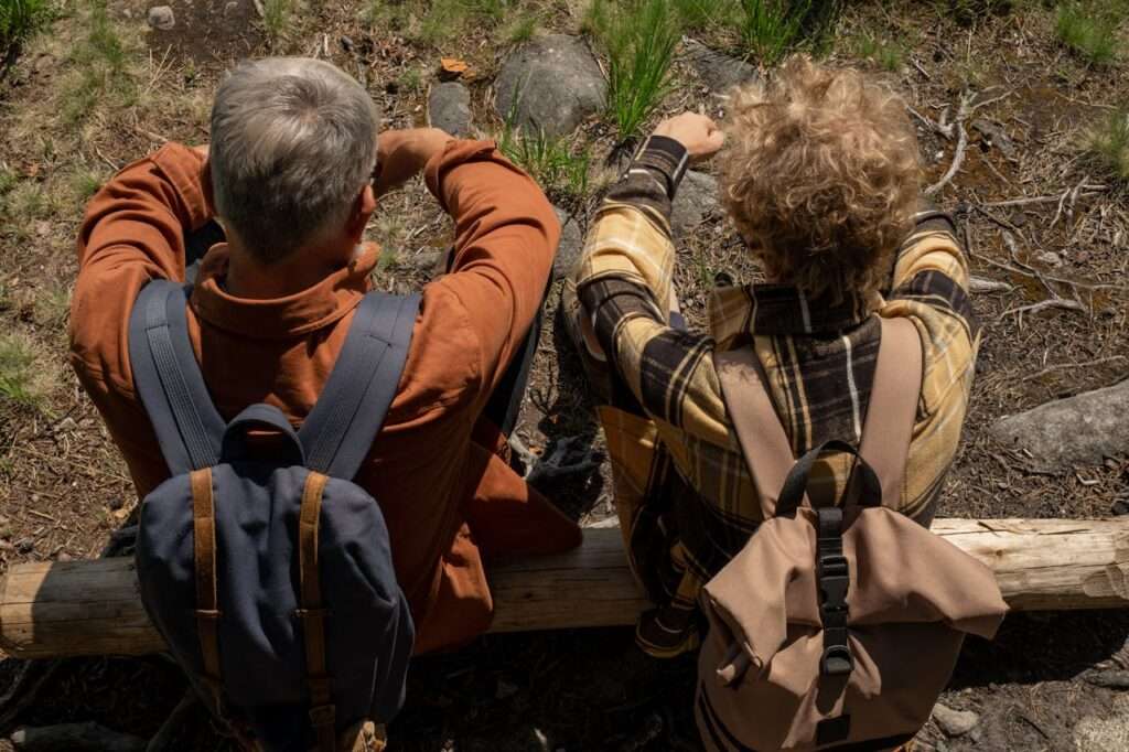 adulto e jovem de costas, com mochila, sentados