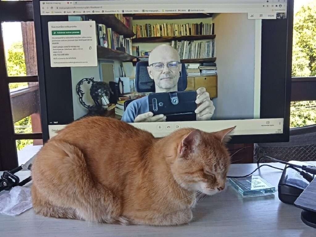 gato café tendo como fundo uma tela e um homem careca