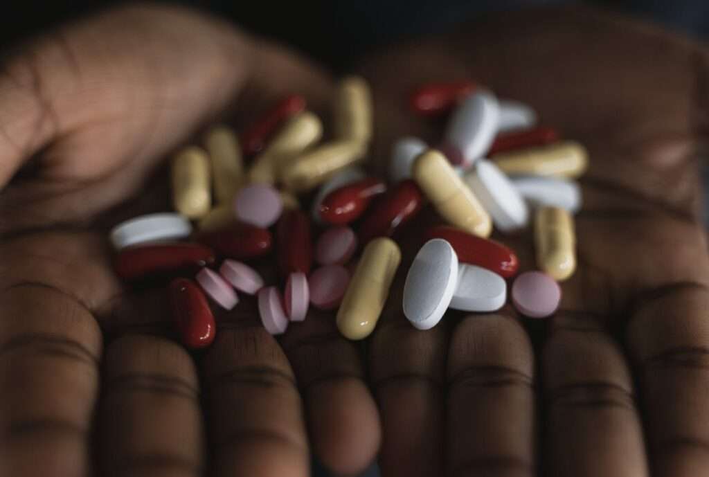 mãos de pessoa negra com vários medicamentos