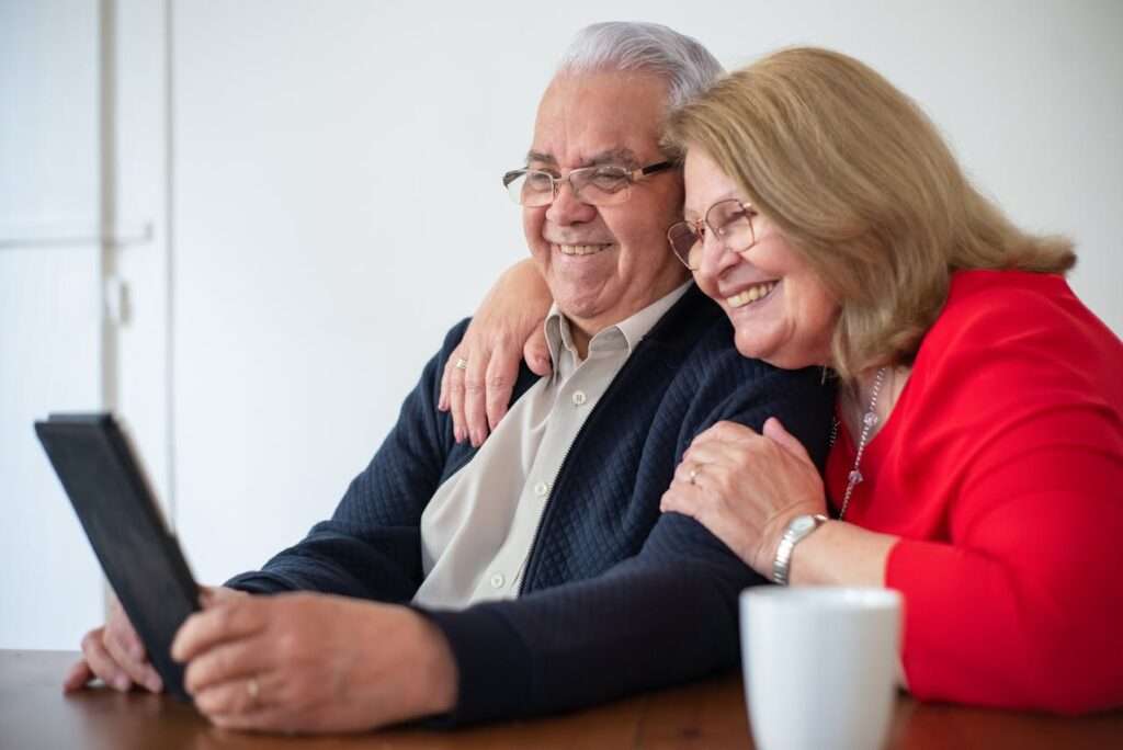 casal de idosos, sorrindo, olham para o tablet