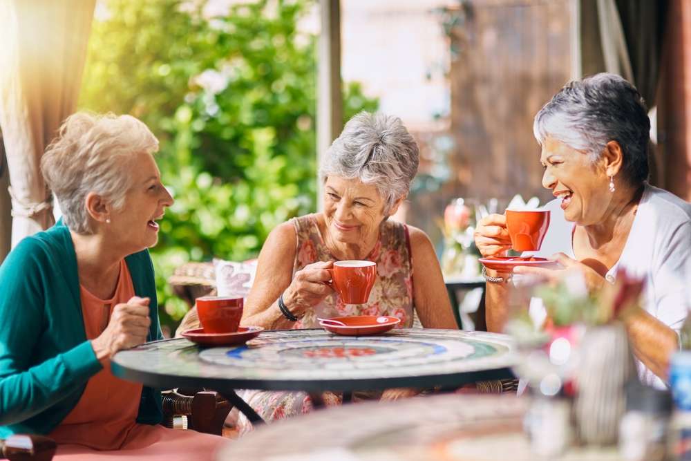 3 senhoras idosas tomam chá enquanto sorriem