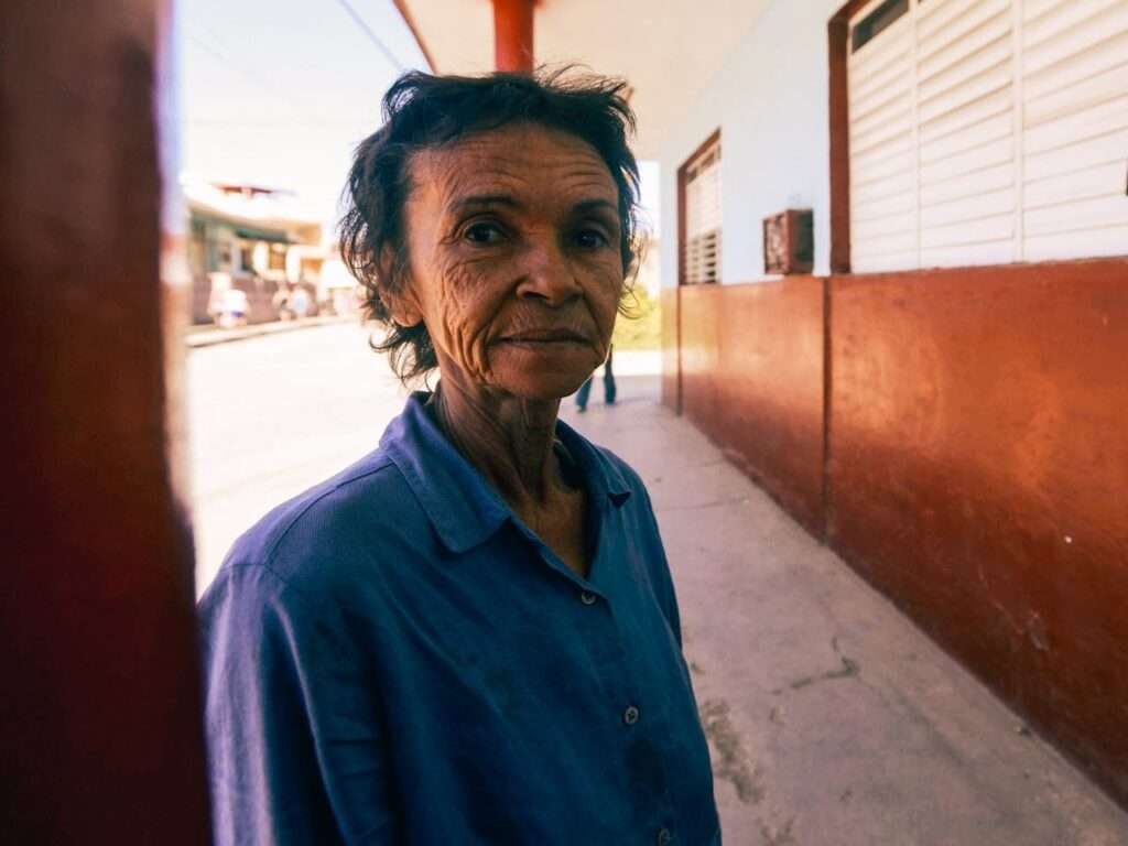 idosa, cabelo curto, camisa azul, olha para a foto