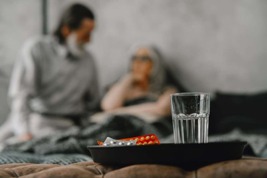 casal de idosos difuso tendo medicamentos e copo de água como foco