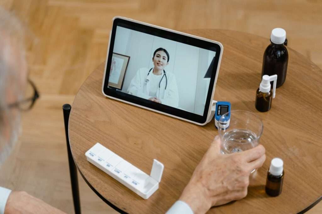 tela em tablet de médica e pessoa idosa de costas e sobre a mesa medicamentos