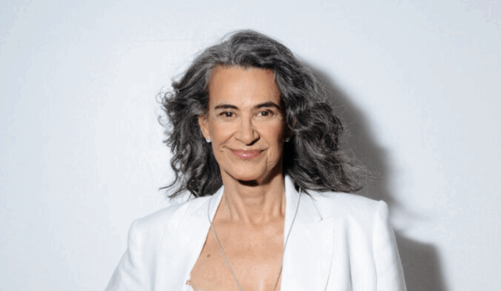 mulher de cabelos grisalhos olha para a camera, vestindo branco