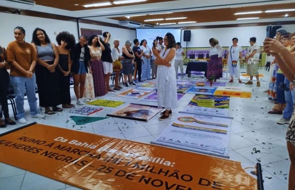 varias mulheres e ao centro uma de branco e no piso baneres