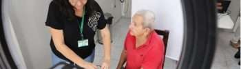 pessoa idosa de camisa vermelha em urna eleitoral acomapnhada