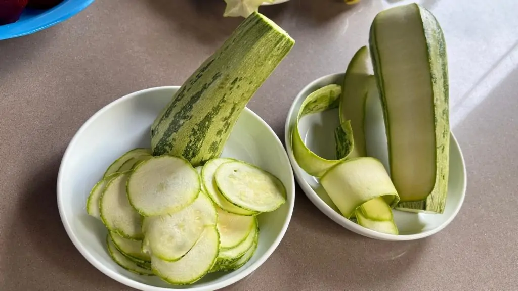 abobrinha semi inteira e cortada em rodelas dentro de pratos brancos