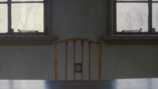 uma cadeira, vazia, em uma sala com duas janelas abertas