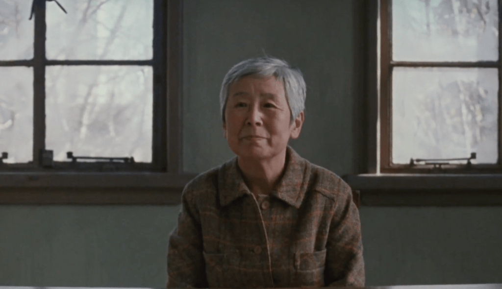 idosa de cabelo branco e curto, sentada, olha serenamente para a camera